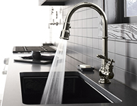 Decorative faucet running water into a built-in kitchen sink.