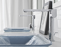 Decorative bathroom glass sinks with silver faucet and the same sink in the background.