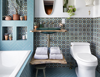 Decorative green glass sink with a brown countertop next to a decorative toilet and bathtub.