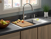 Decorative built-in kitchen sink with a silver faucet that has a cutting board over half the sink.